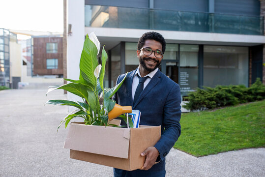 Happy businessman with his belongings leaving office building