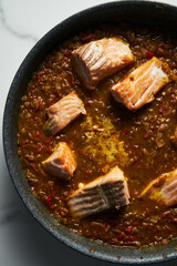 Frying pan with Indian salmon curry dish. Fried salmon fillets, stewed in curry sauce based on red tomatoes and other vegetables. Top view close up.