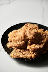 Raw Chicken schnitzel billet es calliope in breadcrumbs. On white marble background.