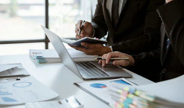 negotiation, analysis, discussion,asian male economist using report explaining the investment finance program to the company owner to plan marketing and hedging business risks.