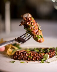 Shallow focus of an octopus on fork served on a white plate
