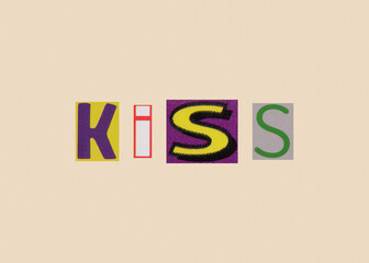 Kiss word from cut out magazine colored letters on a light background