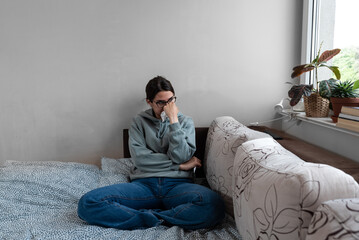 Fototapeta na wymiar Ill upset young woman sitting on sofa covered with blanket freezing blowing running nose got fever caught cold sneezing in tissue, sick girl having influenza symptoms coughing at home, flu concept
