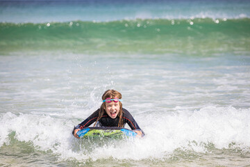 Young girl bodyboarding in St Ives, Cornwall