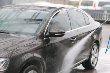 Car washing. Cleaning car using high pressure water. Man washing his car outdoor. Close-up