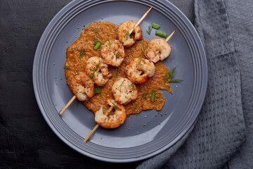 Grilled prawns on skewers on the plate, seafood snacks. Seafood barbecue, roast shrimps top view