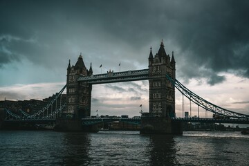 Scene of the Tower Bridge reflected on the River Thames under a cloudy sky in London, UK