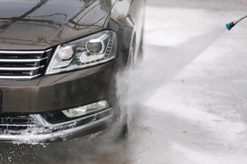 Worker cleaning car using high pressure water. Close up