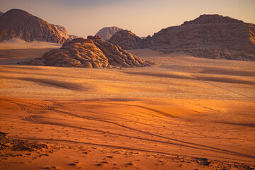 Wadi Rum w Jordanii. Ślady na gorącym pustynnym piasku na tle formacji skalnych. - obrazy, fototapety, plakaty