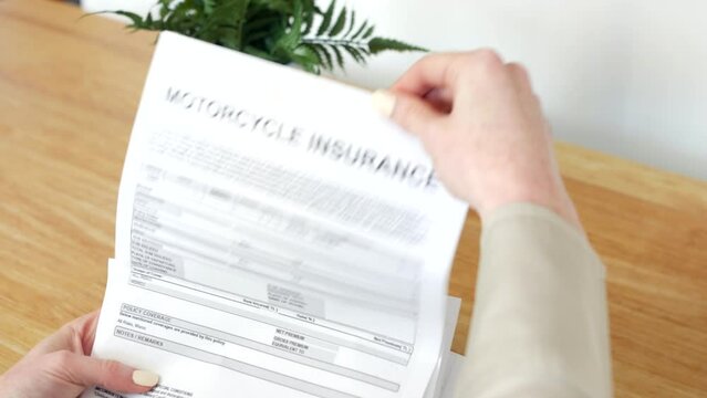 A woman opening a motorcycle Insurance Document letter outlining her policy and cover details