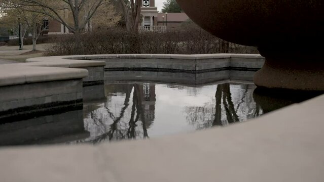 Fountain with still water on the campus of Ole Miss in Oxford, Mississippi with stable establishing shot.