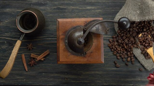Wooden spoon pours coffee beans into an coffee grinder