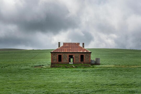 Cobb and Co Coach House Hotel in a green field under a cloudy sky in Burra, Australia