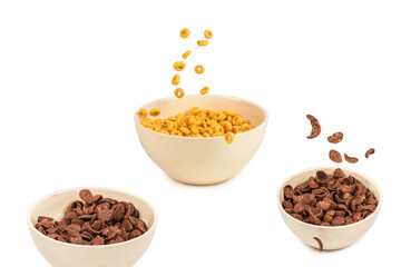 Chocolate corn flakes falling to the white bowl isolated on white. Motion.