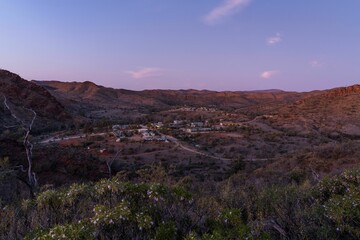 Landscape of mountains and trees under the sunset sky.