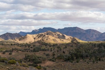 Landscape of mountains and trees under the cloudy sky.