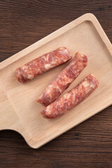 Raw Taiwanese sausage in garlic flavor in a plate on wooden table background.