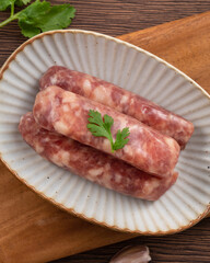 Raw Taiwanese sausage in garlic flavor in a plate on wooden table background.