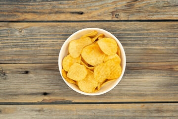 Close-up, a plate with potato chips on a wooden background, top view.
