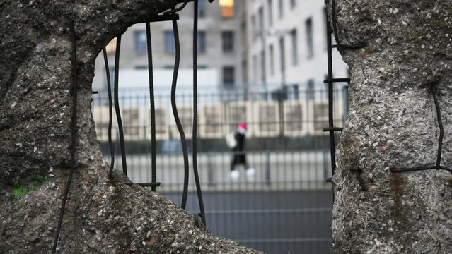 Hole in Broken Berlin wall and walking person against. Concept of freedom and independence.