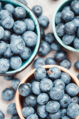 Three ceramic bowls with blueberries and berries scattered around. Top view.