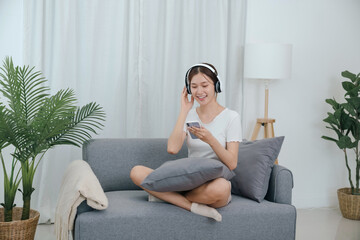 Young asian woman with headphones relaxing at home. listening to music