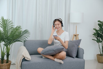 Obraz premium Young asian woman with headphones relaxing at home. listening to music