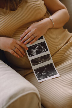 Close-up of pregnant belly and sonogram photo in hands of mother. Concept of pregnancy, maternal health