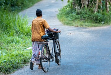 Obraz premium Man walking beside his bike on a countryside road