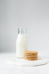 Oat cookies next to milk bottle, homemade oatmeal cookies, thin oat biscuits and milk