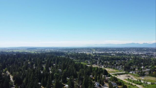 A peaceful aerial view of a developing neighbourhood in Surrey, BC with houses nestled amongst lush green scenery and majestic mountain ranges.