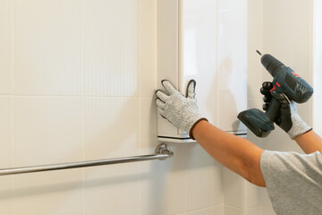 Handyman installing cabinet on bathroom wall..