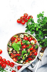 Quinoa tabbouleh salad with red cherry tomatoes, orange paprika, avocado, cucumbers and parsley. Traditional Middle Eastern and Arabic dish. White table background, top view