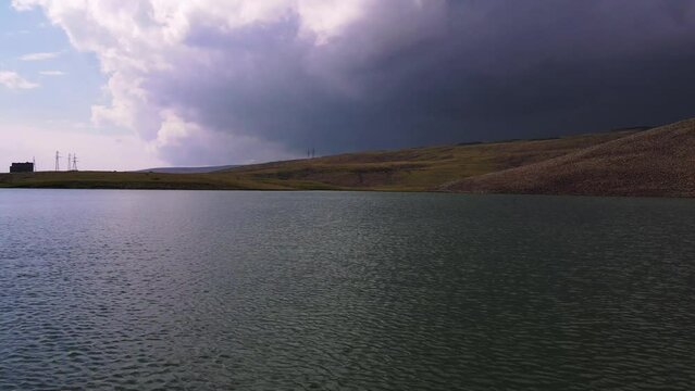 Aerial of the lake on top of the Aragats Mountain with the dark gloomy sky in the background