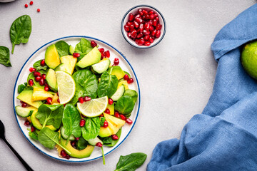 Vegan salad with pineapple, spinach, avocado and pomegranate, gray table, top view. Healthy eating, clean food, diet, weight loss concept