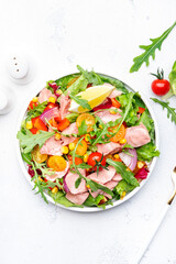 Fototapeta na wymiar Canned Tuna salad with colorful cherry tomatoes, red onion, sweet corn, paprika, lettuce, radicchio and arugula. White table background, top view