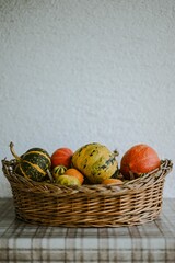 Vertical closeup of a various pumpkins in a basket on a checkered tablecloth