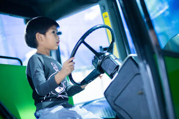 A boy learning to drive a model car in a museum