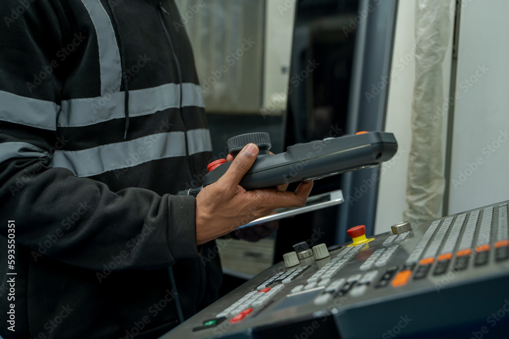 Poster Engineer using laptop computer controlling automated robot hand with CNC machine in smart factory.