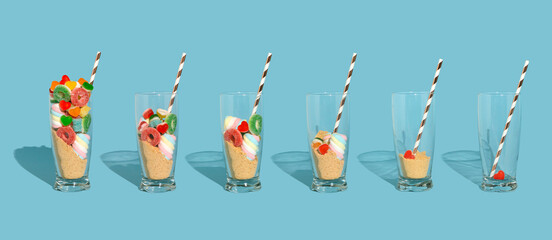 Party concept glasses with gummy candies, hearts, marshmallows and ground biscuits. Candy shake on blue background.
