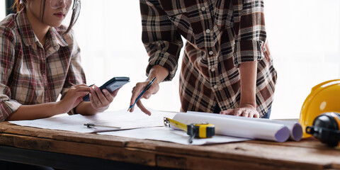 Architect and Engineer working with blueprints for architectural plan, engineer sketching a construction project, green energy concept