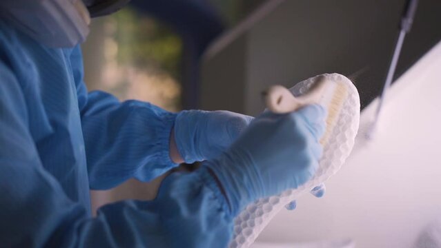 Scientist cleans 3D printed shoe sole, removing excess material and perfecting the final product.