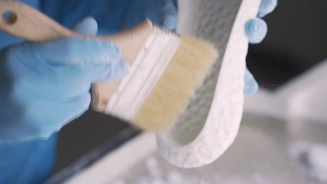 Scientist cleans 3D printed shoe sole, removing excess material and perfecting the final product