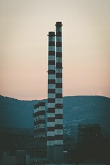 Vertical shot of power factory chimneys in an industrial area at sunset
