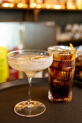 Vertical closeup of two alcoholic cocktails on a tray. Margarita and Americano.