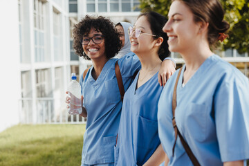 Diverse, happy female students coming from class in medical scrubs