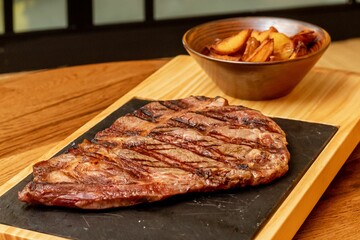 Pice of steak with fried potato on the wooden board.