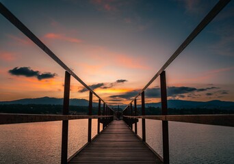 Fototapeta na wymiar Long exposure shot of a wooden bridge over a lake under dusk sky at sunset in Jalisco, Mexico