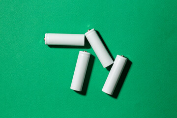 White size AA batteries on a green background top view.