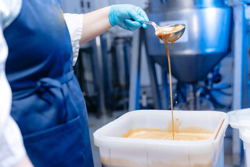 Worker pours honey for brewing mead and beer at brewery